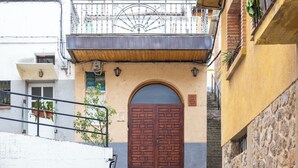 A building with a stone facade, a wooden door, and a balcony with a metal railing.