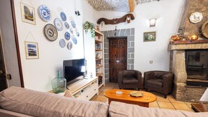 A cozy living room with a sofa, two armchairs, a television, and a fireplace.