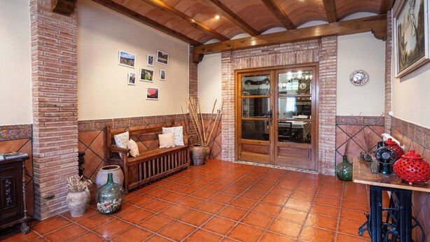 A cozy room with a wooden bench, a tiled floor, and a brick wall.