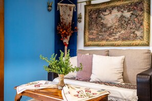 Relax in this inviting space with a comfortable sofa, decorative tapestry, and a beautiful floral arrangement.