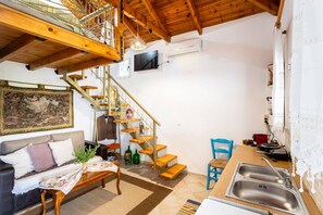 Relax in this stylish living space with a high ceiling, sofa, and modern kitchen area.