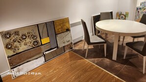 A dining area with a round table and chairs, a decorative wall piece, and a small window.