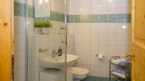Een badkamer met een douchecabine van glas, een wastafel, een toilet en een handdoekhouder.