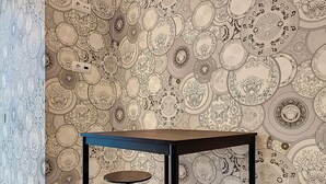 Una habitación con papel tapiz estampado que presenta diseños circulares y una pequeña mesa con dos taburetes.