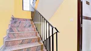 A staircase with marble steps and black railings, leading to a door labeled "First Floor." - DETEEX AVINABA INN (Barasat)