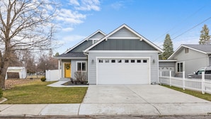 A two-story house with a garage, a front yard, and a white picket fence.