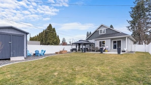 A residential backyard with a covered patio, a shed, and a fenced area.