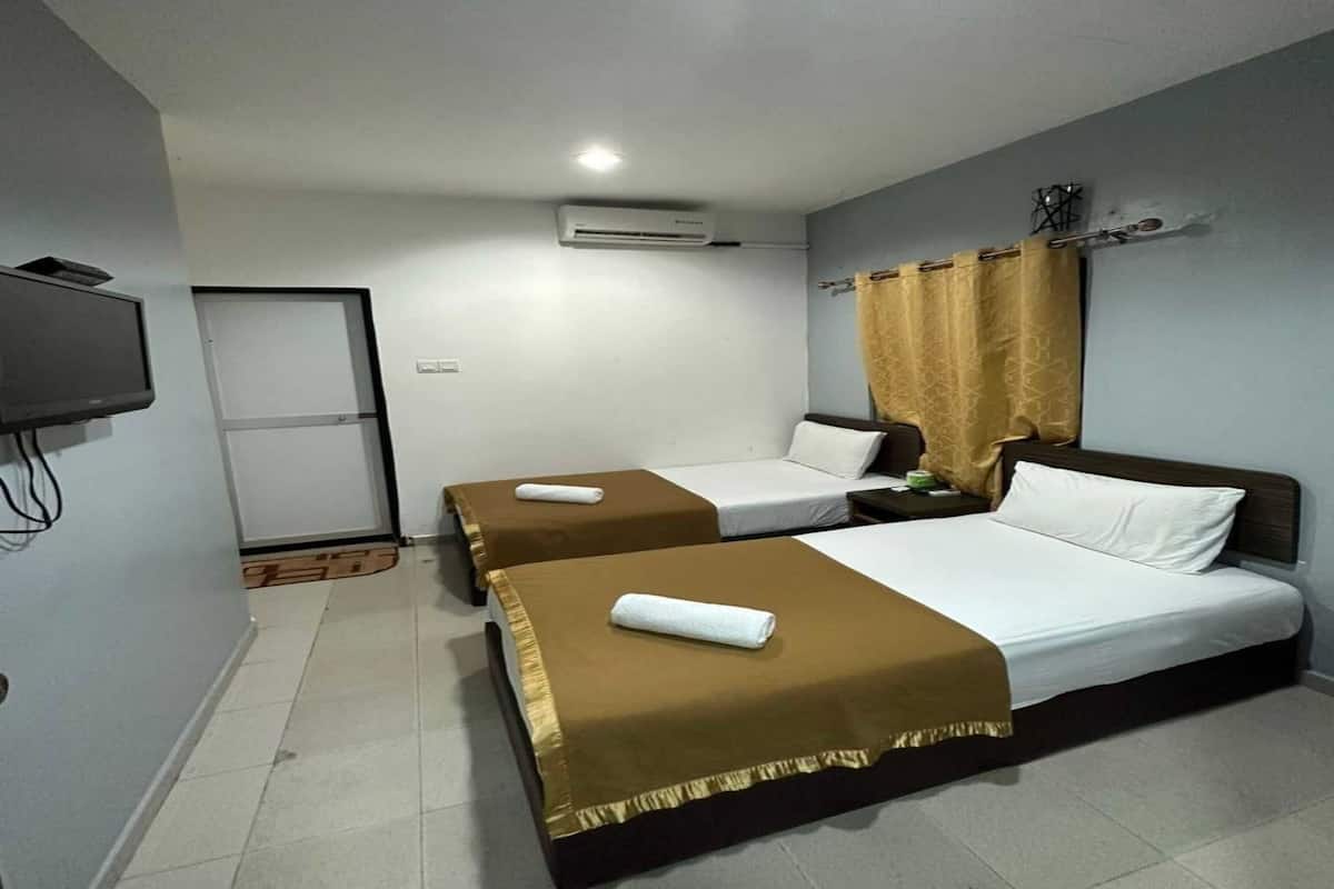 A hotel room with two beds, a television, an air conditioning unit, and a curtain.