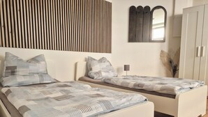 Un dormitorio con dos camas, una pared de listones de madera, un espejo y un armario.