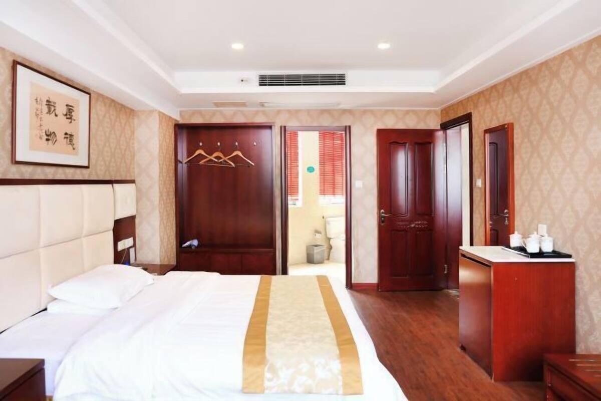 A hotel room with a bed, a desk, and a wardrobe.