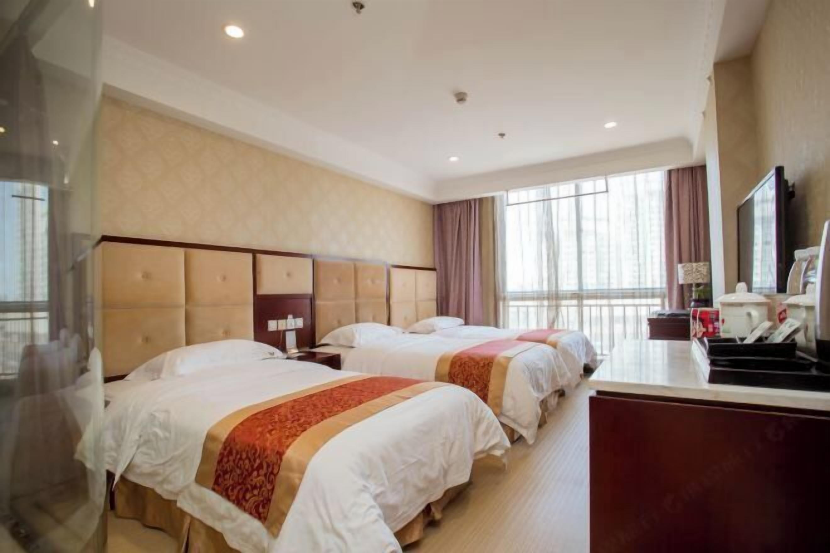 Une chambre d’hôtel avec deux lits, un bureau et une grande fenêtre.