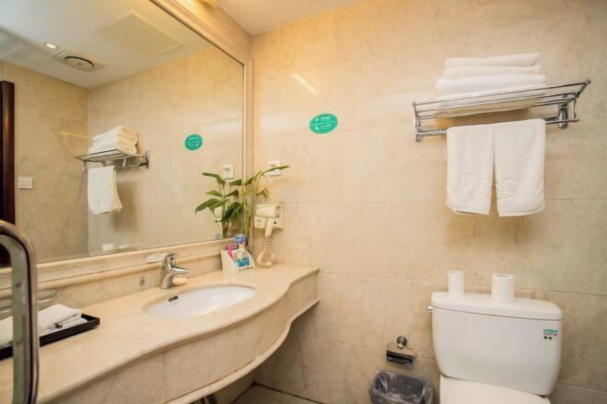 Une salle de bain équipée d’un lavabo, d’un miroir, d’un porte-serviettes, de toilettes et d’une poubelle.