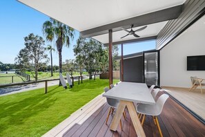 Un área de comedor al aire libre moderna con una terraza de madera, una mesa grande y sillas.