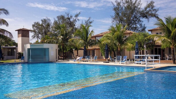 Ein Swimmingpool mit klarem, blauem Wasser, umgeben von Liegestühlen und Palmen.