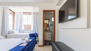 Ein Hotelzimmer mit zwei Betten, einem Fernseher, einem Badezimmer und einem Schreibtisch.