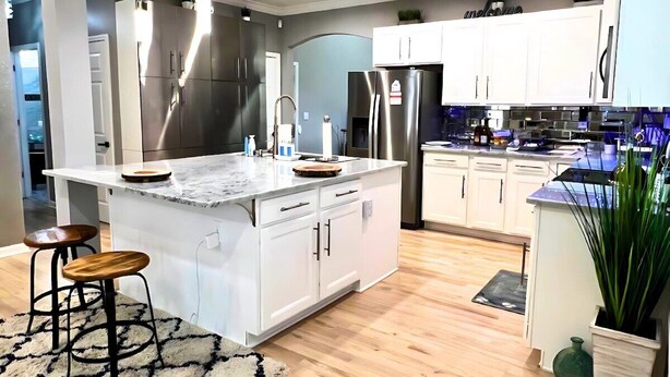 A modern kitchen with white cabinetry, stainless steel appliances, and a marble island with stools. - Luxe 4 Bed ATL Retreat - Pool, Fire, Sauna, Theater (Atlanta)