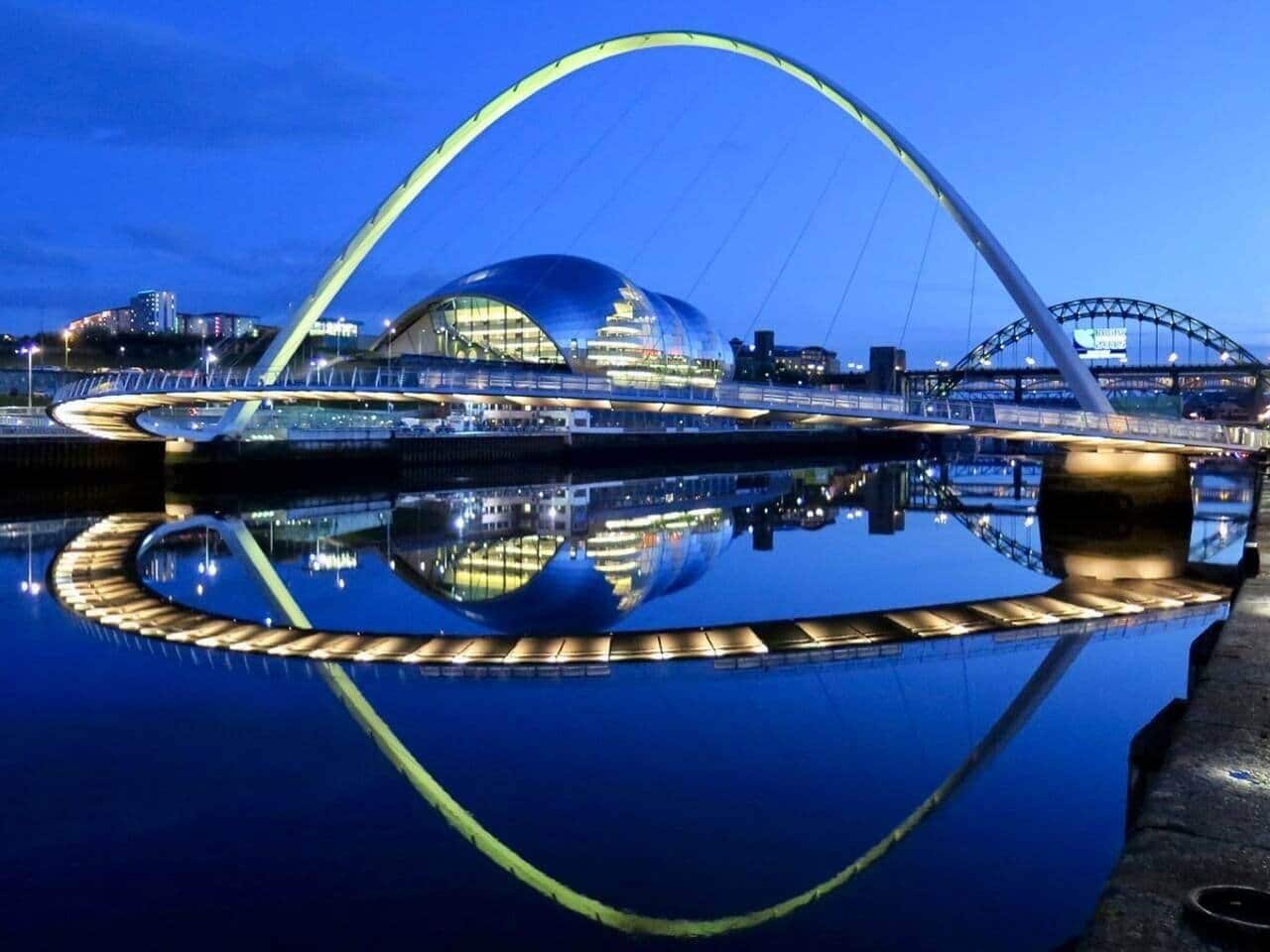 A modern architectural structure with a large, curved roof and a circular water feature below.