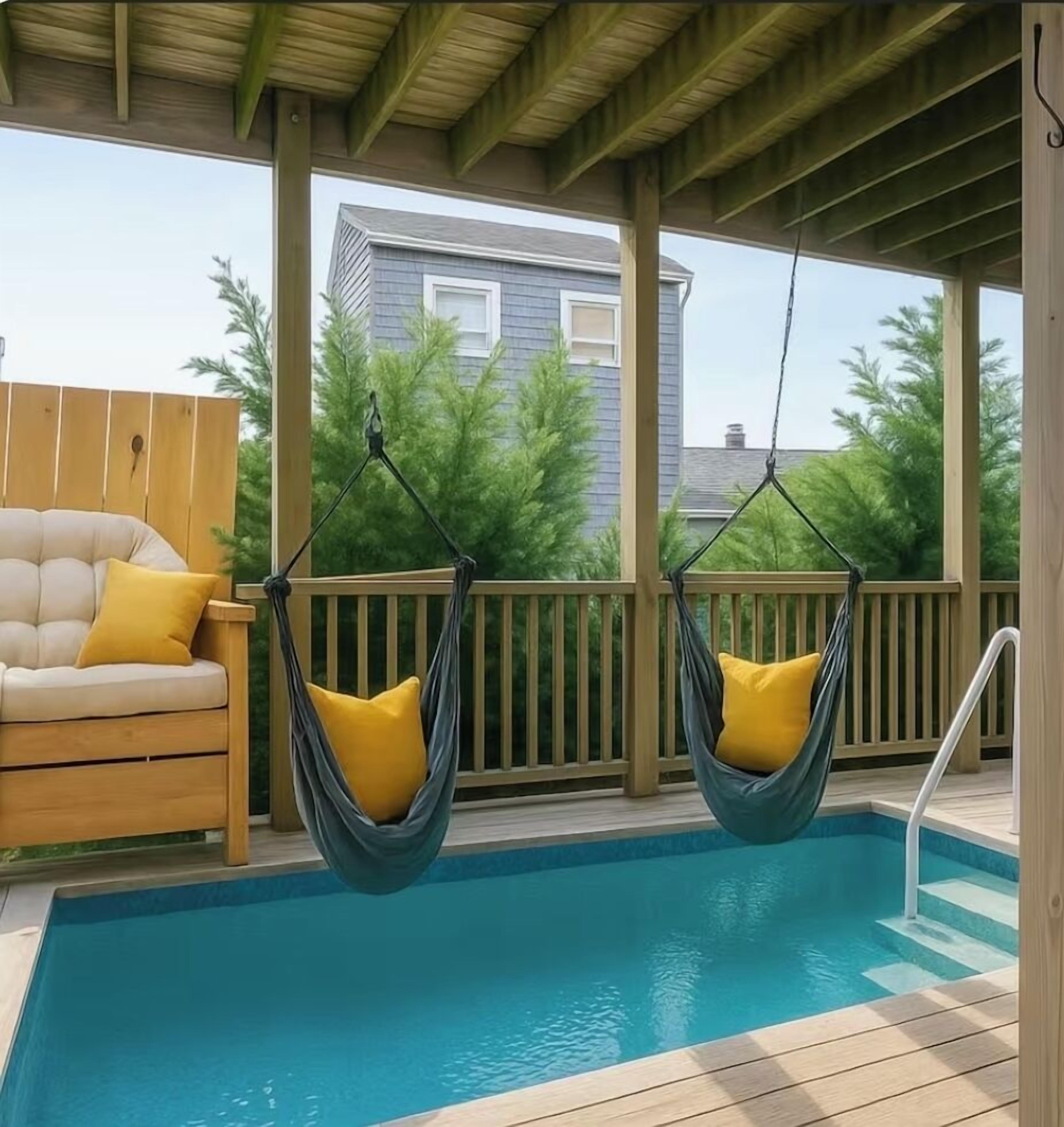 A pool area with two hanging hammocks and a wooden deck.