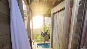 A wooden deck leading to a pool area with a hammock. - Gatsby’s Main Level. Ocean Bay Park. 
Heated Saltwater Pool + Hot Tub. Sleeps 14 (Ocean Beach)