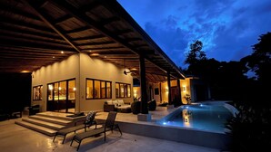 Une maison moderne dotée d’un patio couvert, d’une piscine et d’un intérieur bien éclairé.