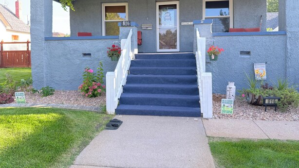 A two-story house with a blue exterior, a front door, and a staircase leading to the entrance.