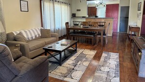 A living room with a sofa, coffee table, and a dining area with chairs and a table.