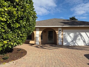 A house with a brick driveway, a garage, and a well-maintained lawn.