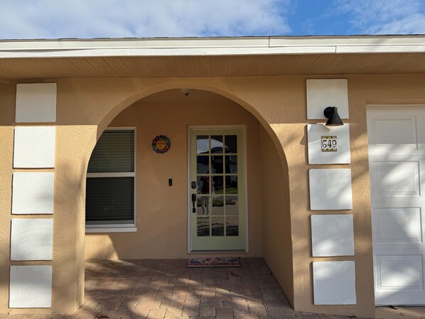 A house with a beige exterior, a white door, and a mailbox with the number 649.