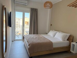 A bedroom with a bed, a TV, a window, and a balcony.