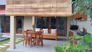 A covered outdoor seating area with a pool, wooden furniture, and a water dispenser. - Umah Landuh, Spacious and comfortable private house near Ubud city (Bali)