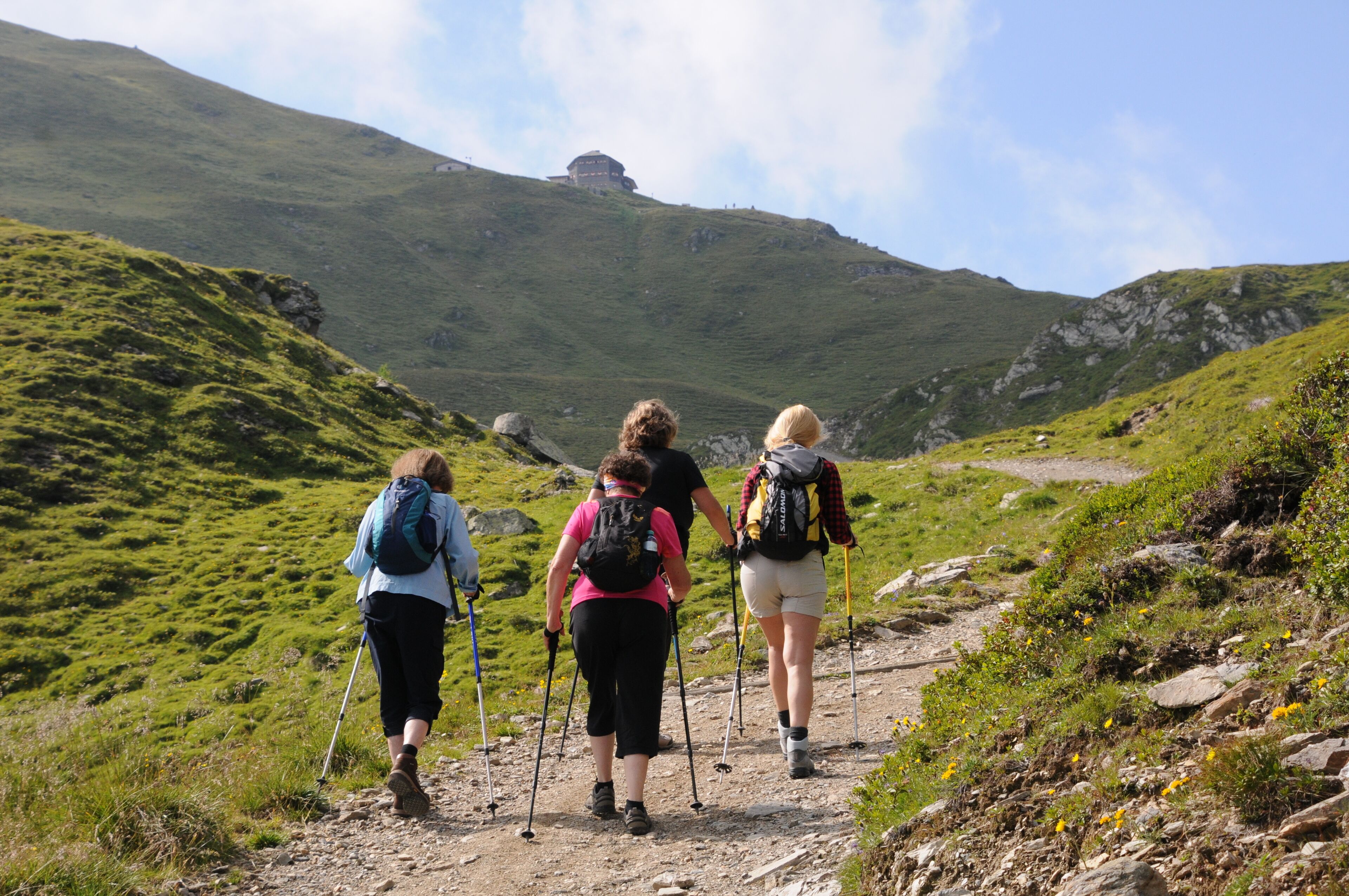 Un groupe de randonneurs sur un sentier de montagne, dans un environnement rocheux et à la végétation clairsemée.