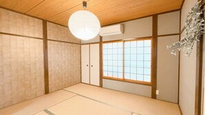 Una habitación japonesa tradicional con suelo de tatami, puertas correderas shoji y un farolillo de papel colgante.
