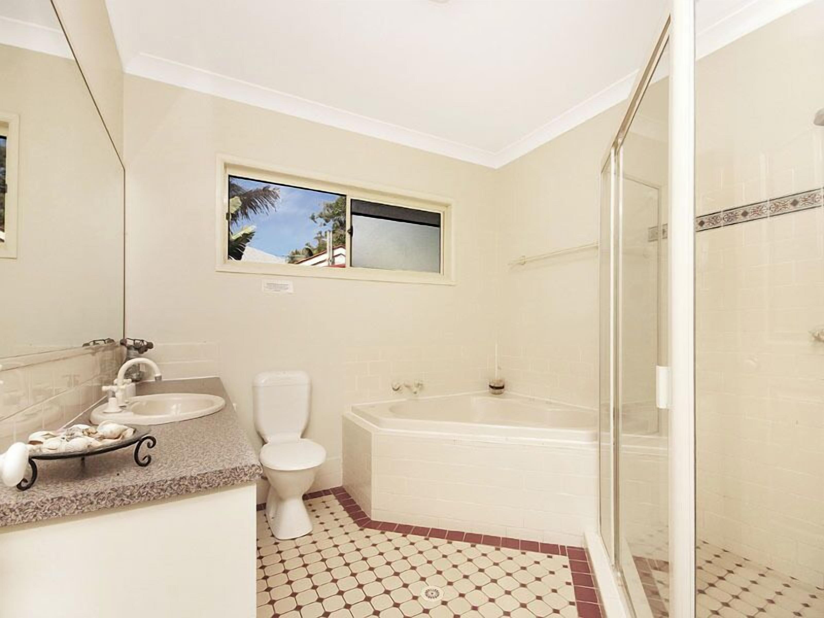 A bathroom with a toilet, sink, bathtub, and a shower area.
