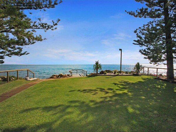 A grassy area with a wooden deck and a view of the ocean. - Relaxing waterfront property with own jetty and magnificent views (Amity Point)