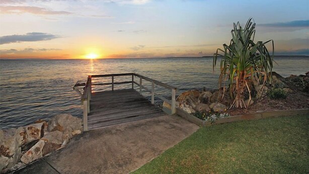 A wooden pier leading to a rocky shore with a palm plant on the right. - Relaxing waterfront property with own jetty and magnificent views (Amity Point)