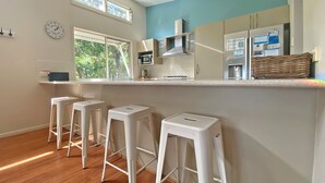 A kitchen with white bar stools, a microwave, and a refrigerator. - Contemporary Beach House in waterfront location (Amity Point)