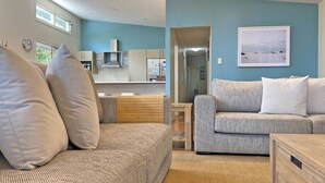 A modern living room with a sofa, a patterned armchair, and a wooden coffee table. - Contemporary Beach House in waterfront location (Amity Point)