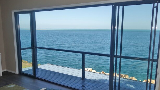 A room with a large sliding glass door leading to a balcony overlooking a body of water. - Large waterfront home with bay views to Moreton Island (Amity Point)