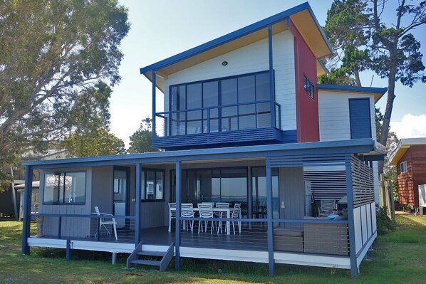 Une maison moderne à deux étages, dotée d’un patio couvert et d’un espace repas.