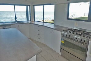 Una cocina moderna con ventanas amplias, estufa a gas y muebles de cocina blancos.