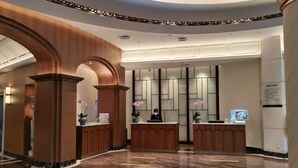 A modern hotel lobby with wooden reception desks, a marble floor, and a decorative ceiling. - Shanghai Hotel (Shenzhen)