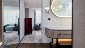 A modern bathroom with a marble vanity, a round mirror, and a geometric pendant light. - Shanghai Hotel (Shenzhen)