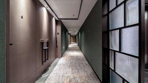 A long, narrow hallway with a patterned floor, green walls, and large windows on one side. - Shanghai Hotel (Shenzhen)