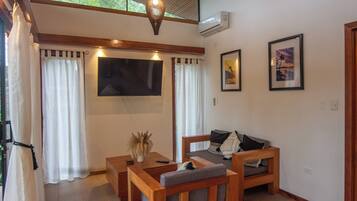 A room with a wooden sofa, a small table, a TV, and two framed pictures on the wall.