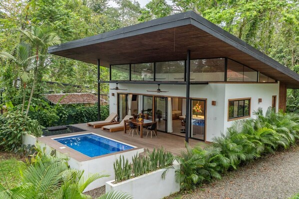 A modern house with a pool, glass doors, and a covered patio.