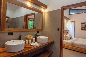 A modern bathroom with two large round sinks, a mirror, and a wooden vanity.