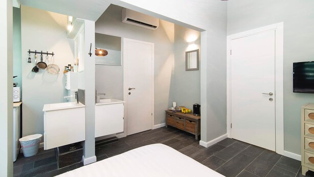 A modern bedroom with a large bed, a built-in wardrobe, a vanity with a mirror, and a small table with a coffee maker. - Raphael City Nest (Tel Aviv)