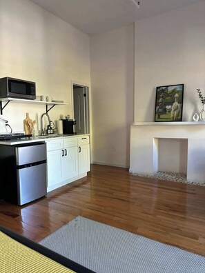 A modern kitchen with white cabinets, a stainless steel refrigerator, and a microwave.