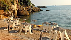 A beach with white canopies and a rocky cliff.