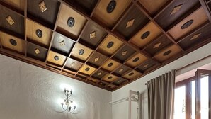 A bedroom with a bed, a nightstand, a wall-mounted light fixture, and a window with curtains.